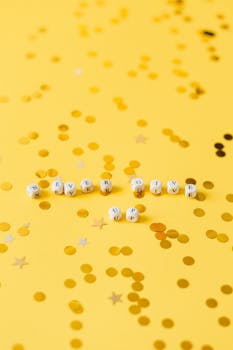 White dice spell out "Never Give Up" on a bright yellow background with confetti.