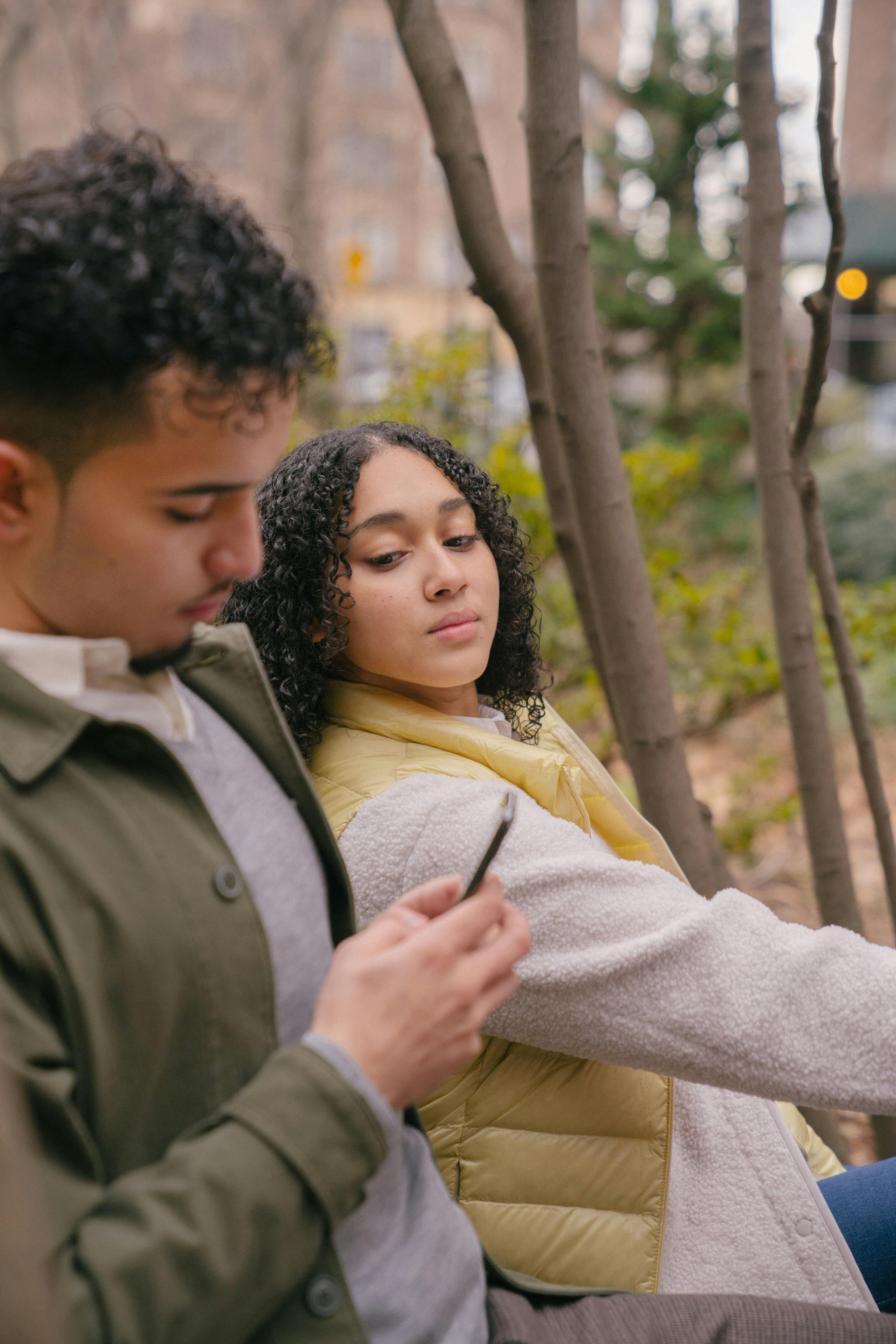 hispanic man using smartphone while woman watching