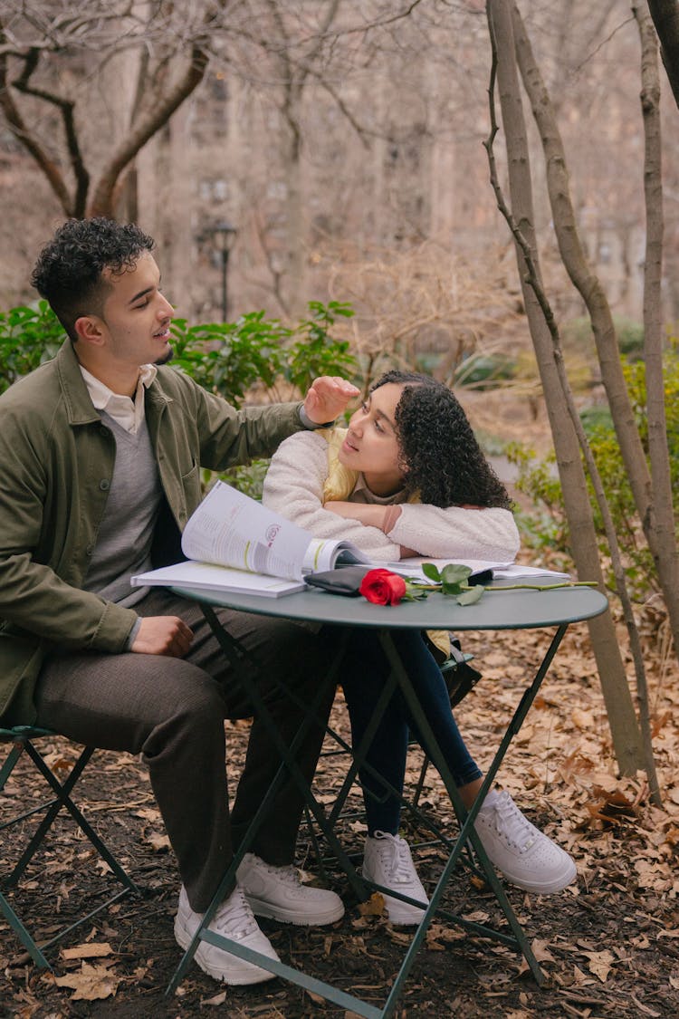 Hispanic Boyfriend Touching Girlfriend At Table With Red Rose