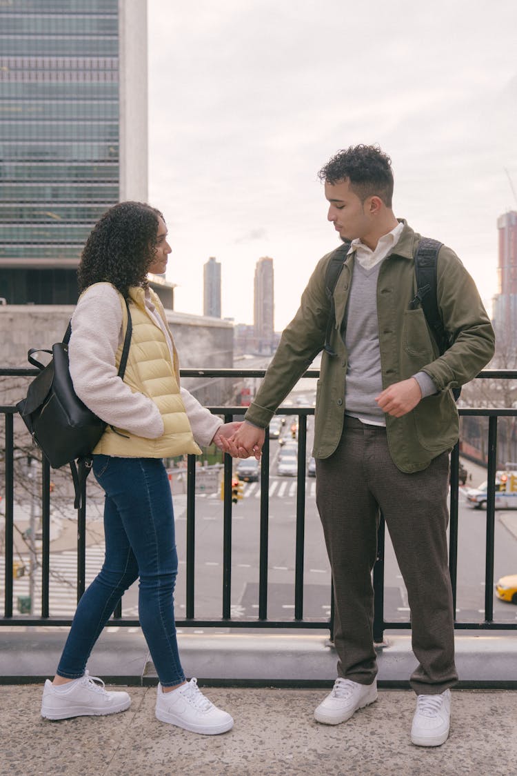 Happy Hispanic Couple Holding Hands On Bridge Of Street