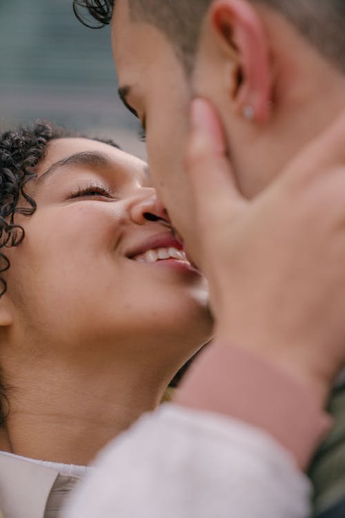 Free Crop ethnic loving gentle couple kissing and hugging each other while smiling on blurred background Stock Photo