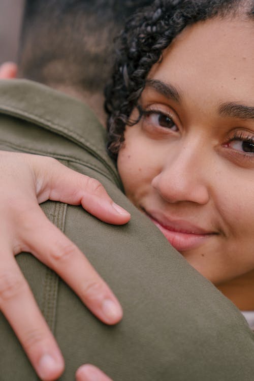 Free Gentle ethnic girlfriend with brown eyes and curly hair smiling and embracing crop anonymous boyfriend Stock Photo