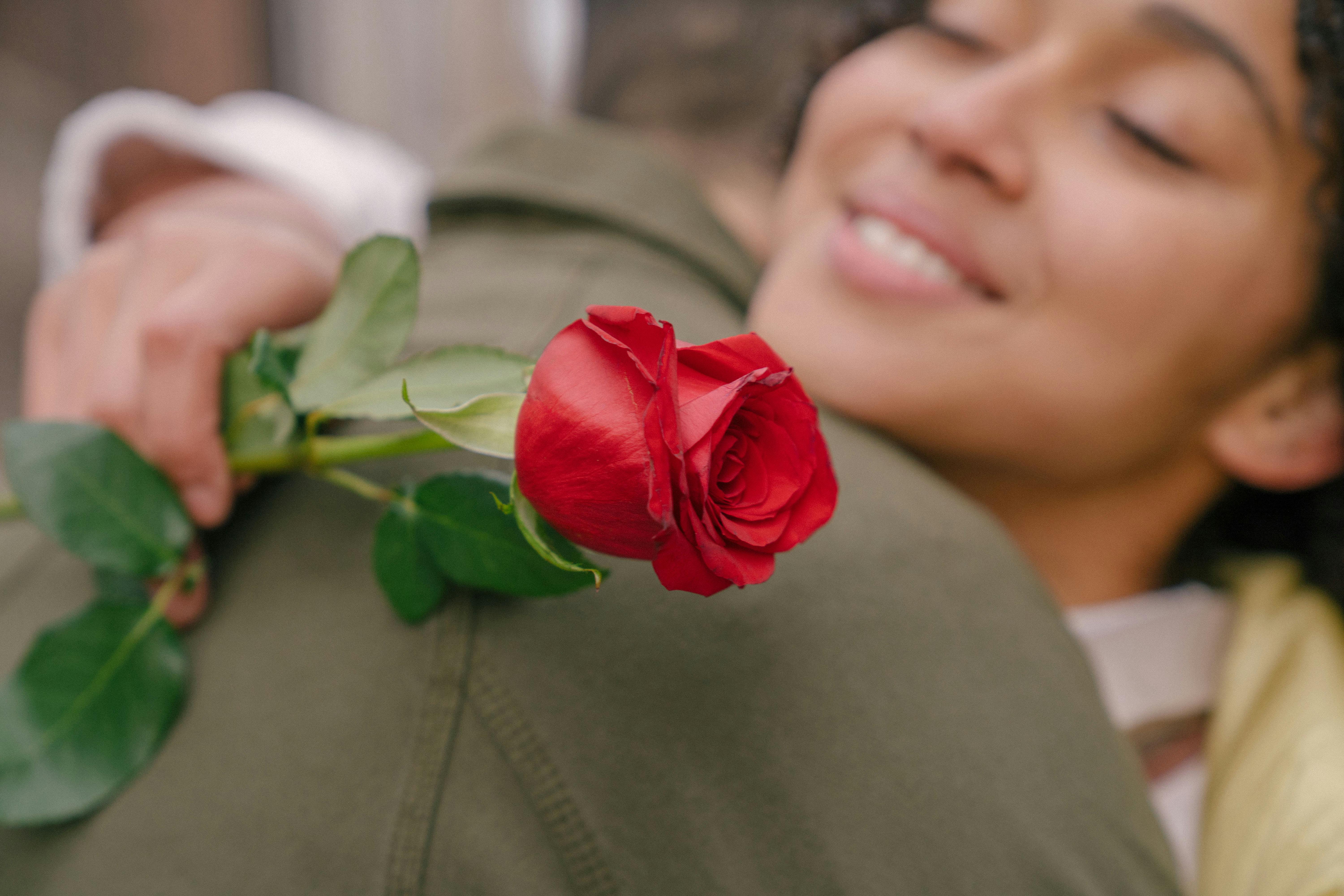 Close-up of a joyful woman hugging with a single red rose symbolizing love and affection.