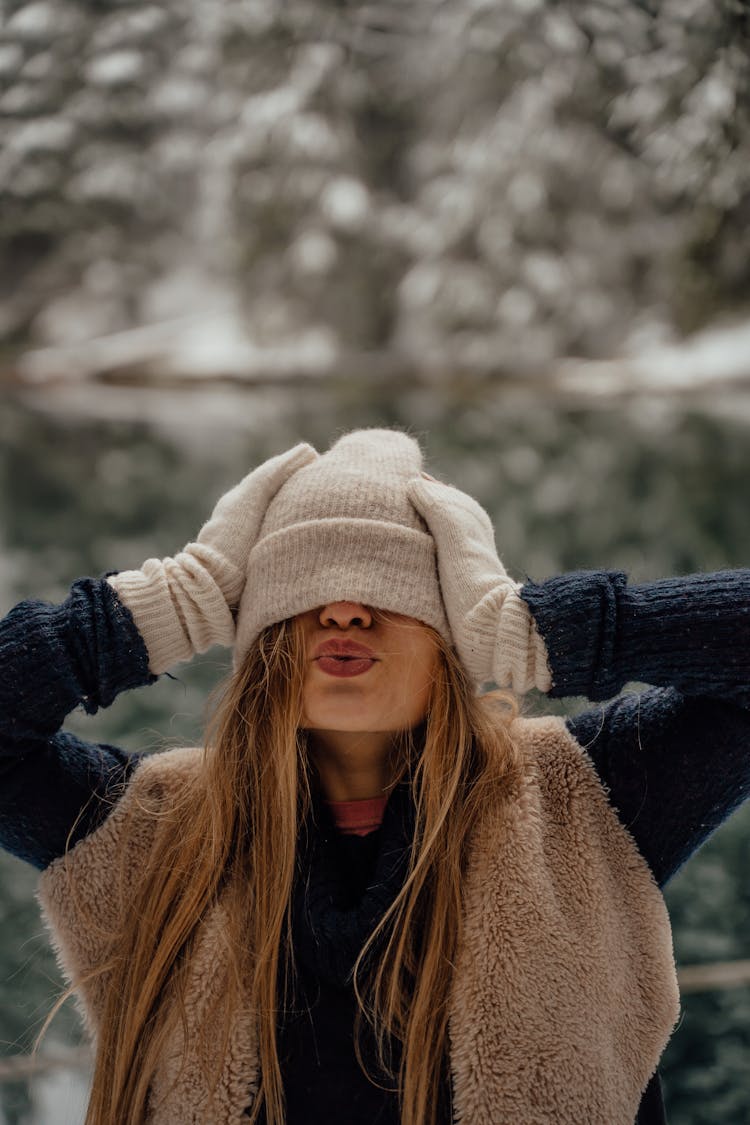 Woman In White Knit Winter Hat And Gloves Blowing A Kiss 