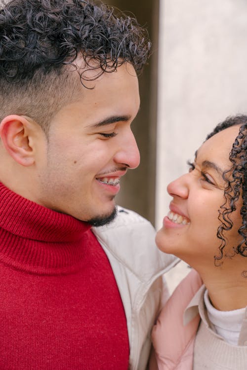 Free Cheerful young Hispanic couple cuddling and smiling on street Stock Photo