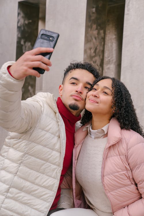 Content young Hispanic couple taking self portrait on mobile phone