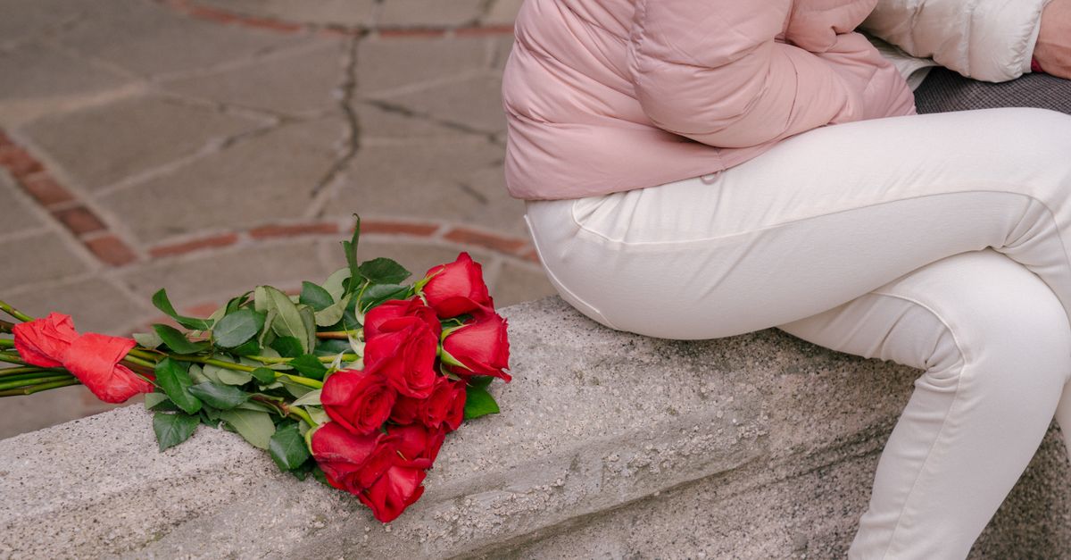 Rüyada Sevgiliden Hediye Almak - Rüya Tabiri ve Anlamı - High angle of crop anonymous couple in casual wear sitting on concrete border near bunch of flowers with bow