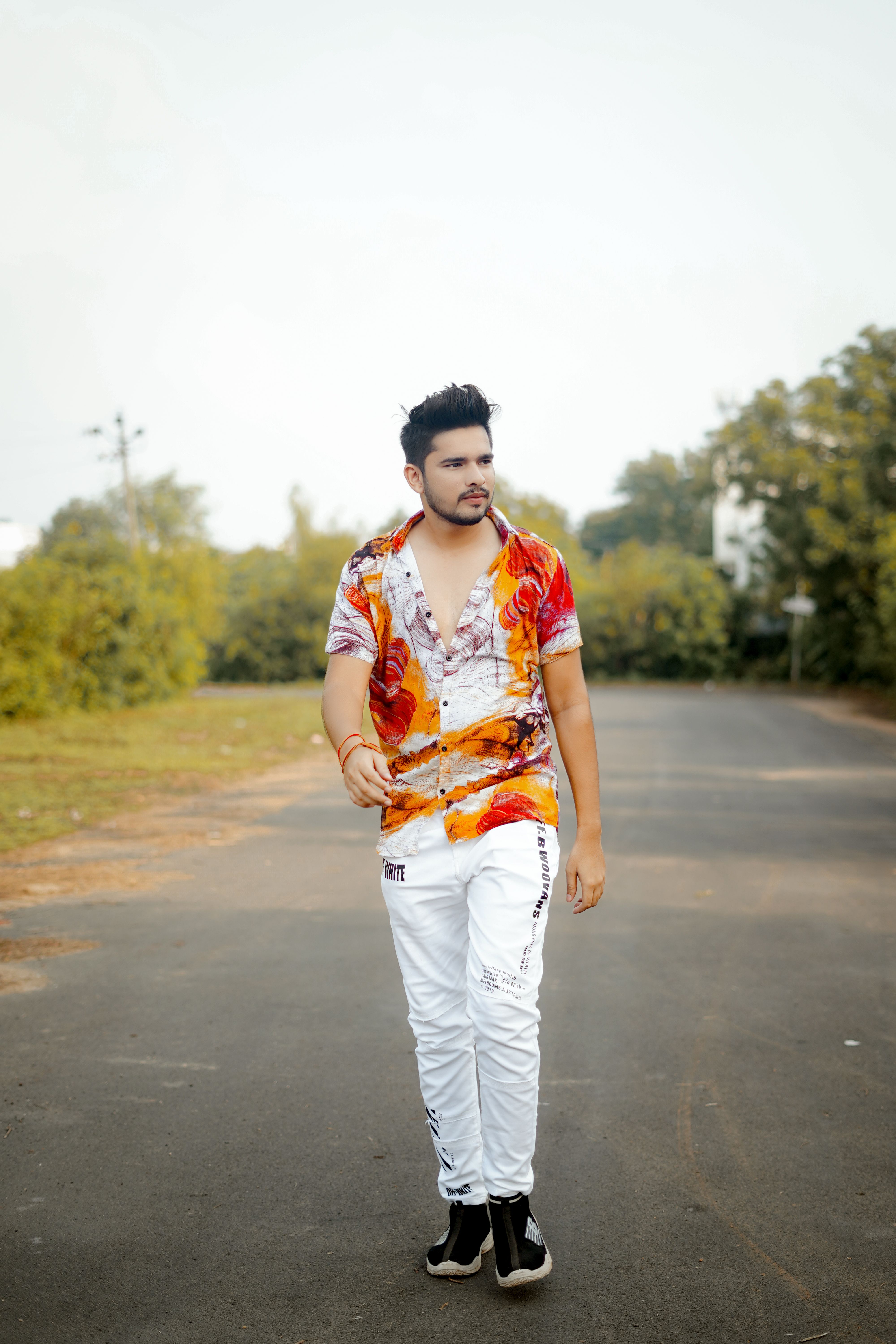 Young man walking on an empty road in Vadodara, showcasing vibrant fashion.