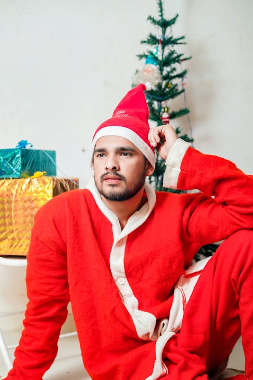 A Man Wearing a Santa Pajama Sitting in Front of a Christmas Tree