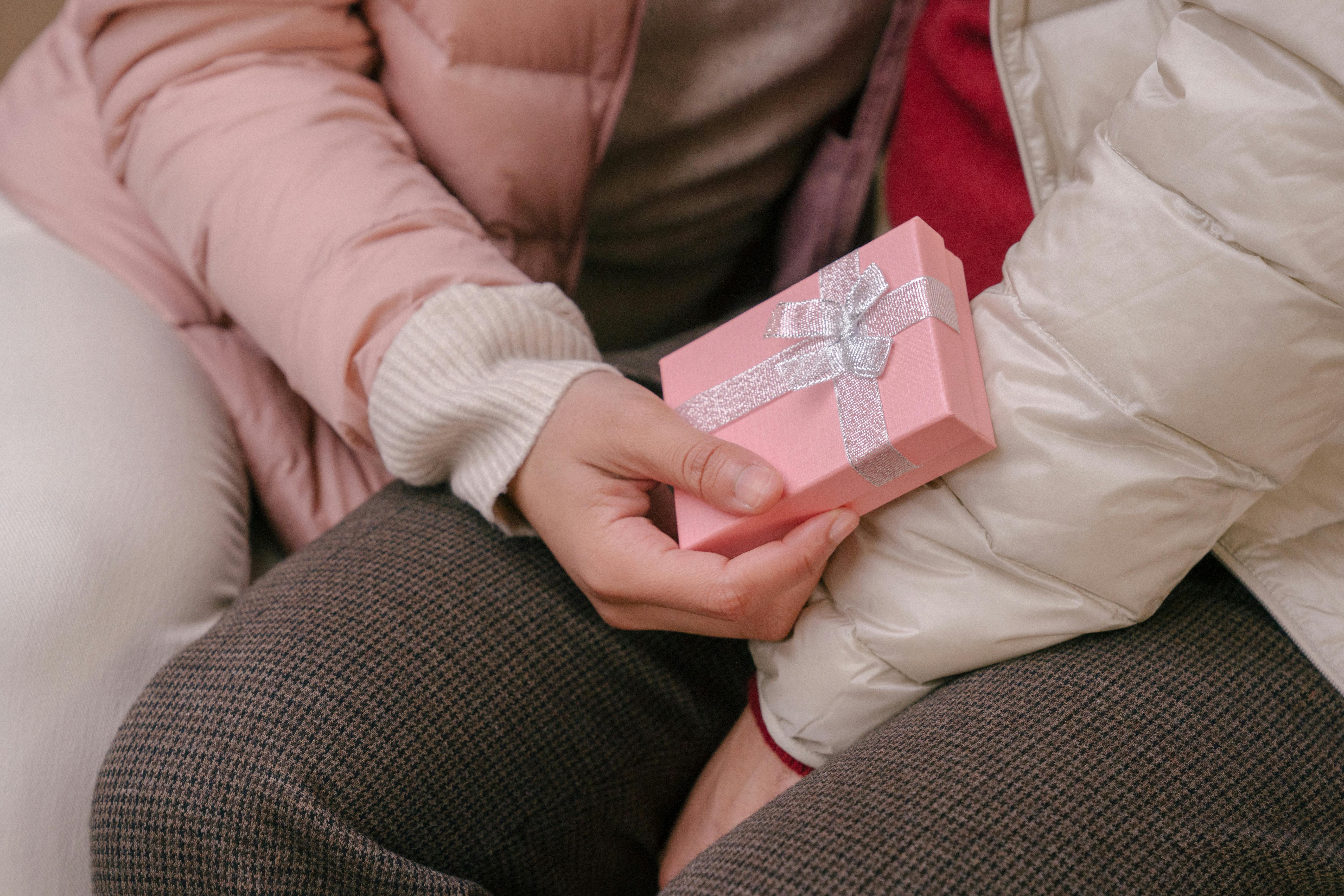 High angle of crop anonymous girlfriend embracing boyfriend sitting with present box gifted for occasion