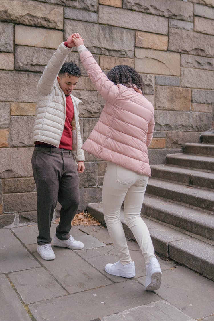 Positive Ethnic Couple Holding Hands And Dancing