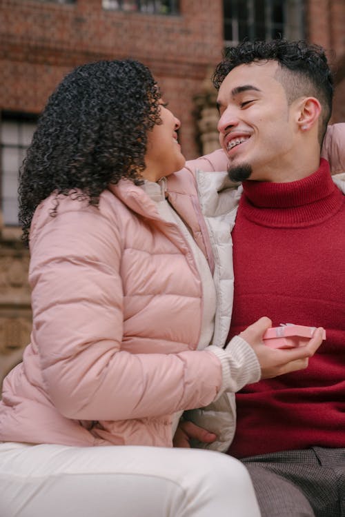 Cheerful ethnic couple embracing gently and smiling to each other