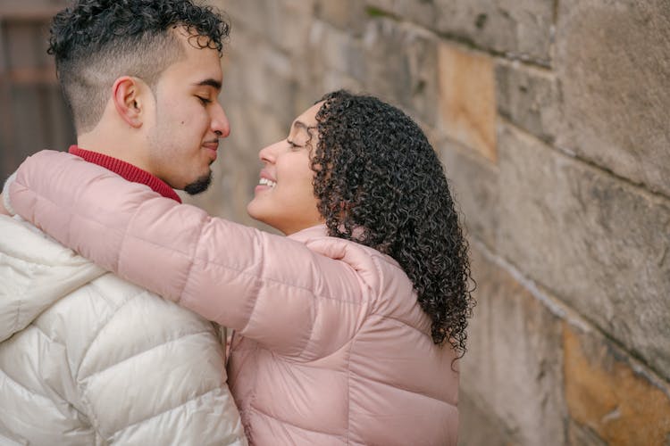 Cheerful Hispanic Couple Cuddling On Street