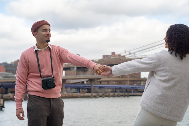 Cheerful Hispanic Couple Holding Hands On Embankment