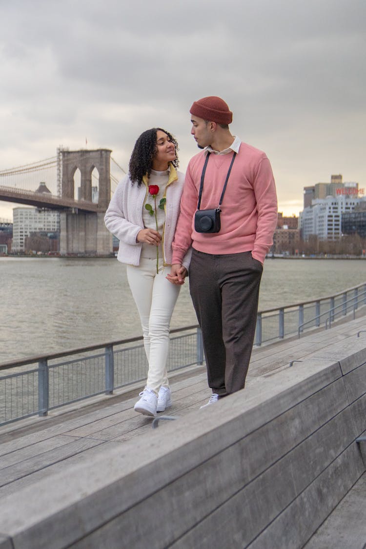 Cheerful Hispanic Couple Walking Along Embankment