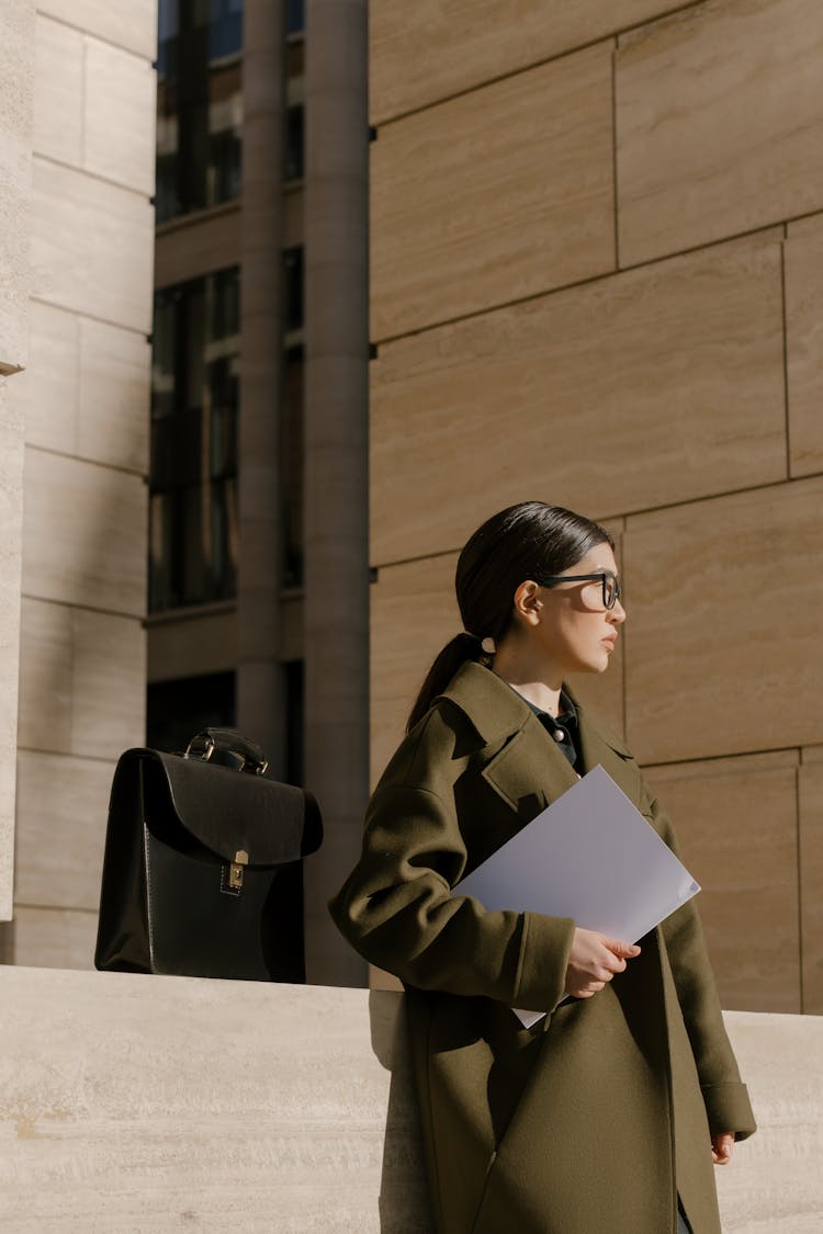 A Woman In Green Coat Holding A Paper