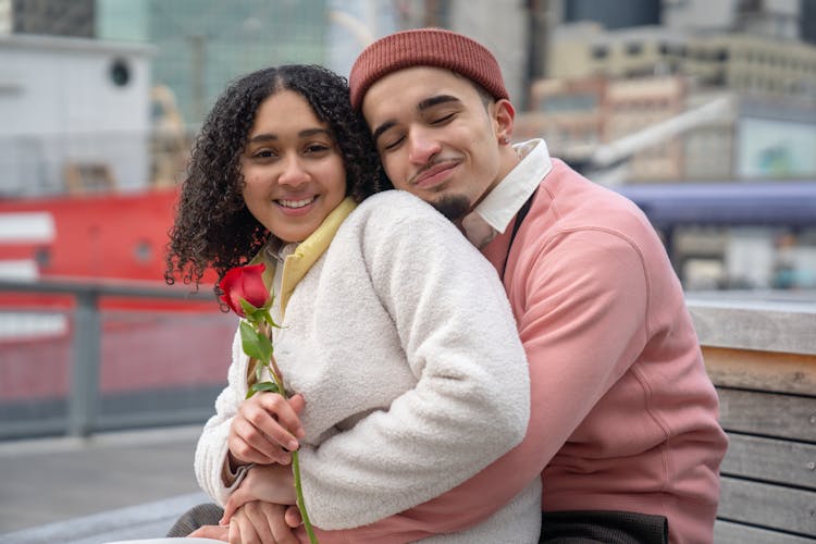 Positive Hispanic Couple Hugging On Bench In Street