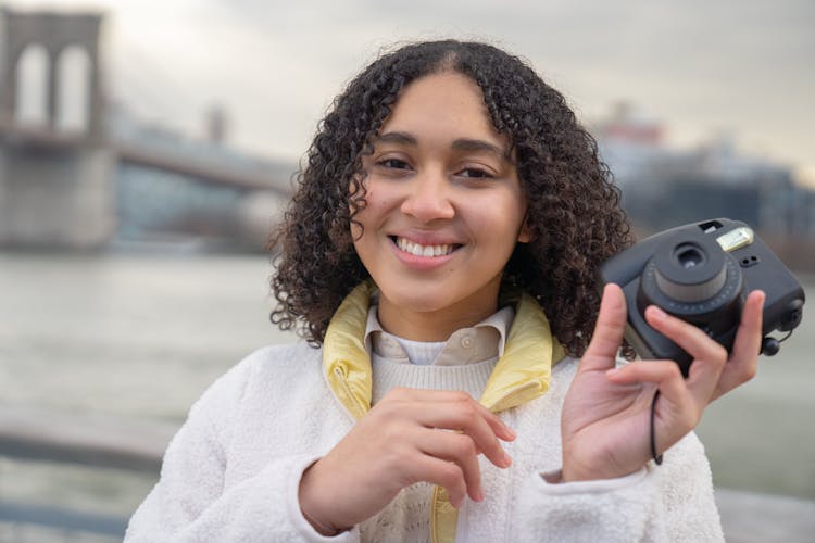 Smiling Hispanic Woman With Photo Camera Standing On Street