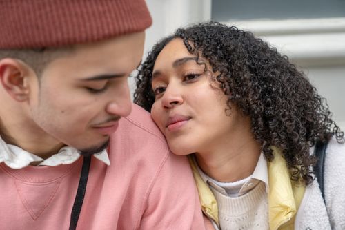 Free Enamored young Hispanic lady with dark curly hair cuddling with crop loving boyfriend while spending time together on street Stock Photo