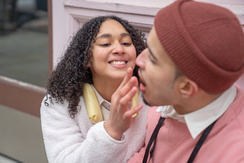 Joyful young Hispanic woman feeding boyfriend on street