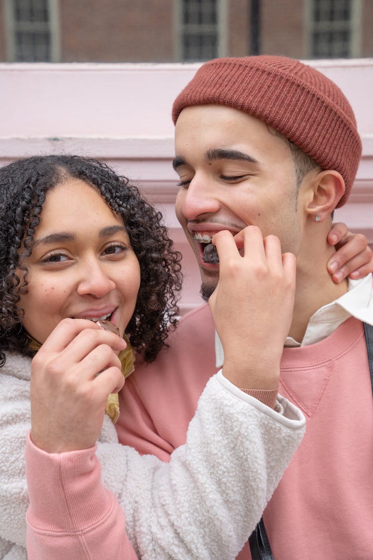 Happy Young Ethnic Couple Feeding Each Other With Chocolates