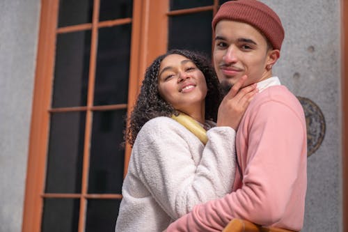 Delighted Hispanic couple caressing on street