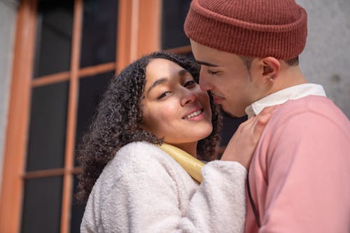 Loving Hispanic couple cuddling near building