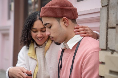 Free Positive Hispanic couple hugging and eating sweet chocolate candy while sitting on street near building in city during romantic date Stock Photo