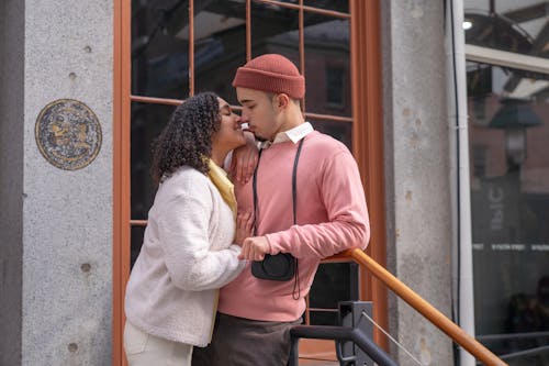 Cheerful Hispanic couple caressing on street