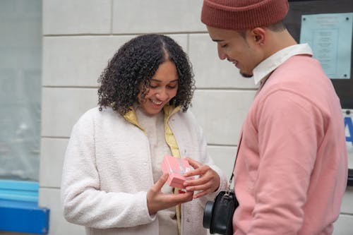 Cheerful Hispanic woman receiving gift from boyfriend