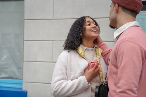 Cheerful Hispanic woman with present near romantic anonymous man