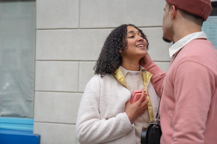 Cheerful Hispanic Woman With Present Near Romantic Anonymous Man