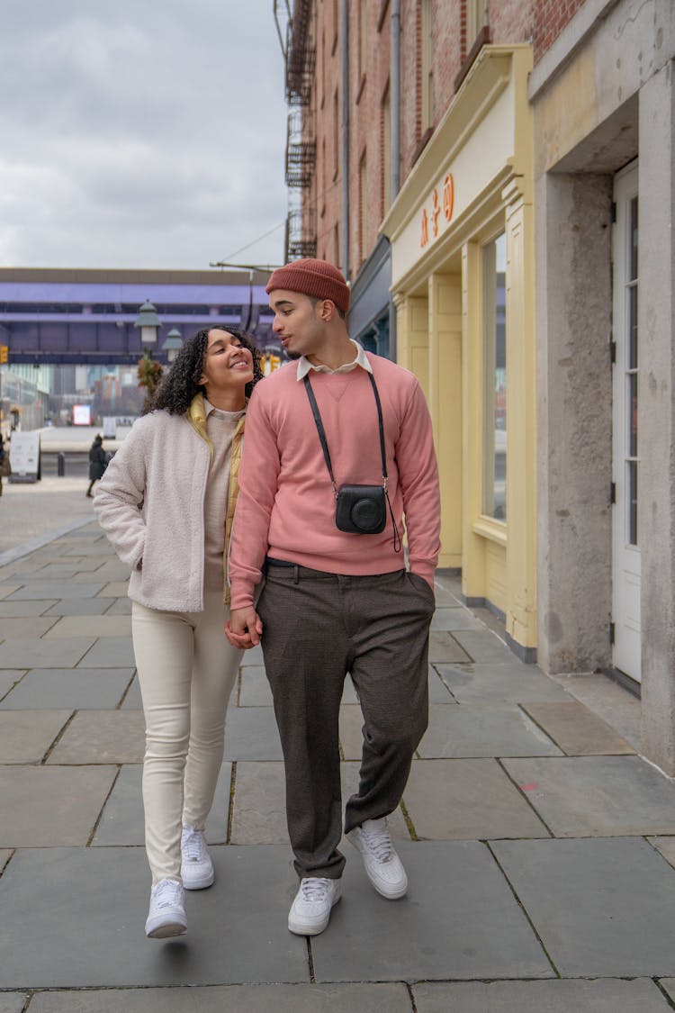 Cheerful Hispanic Couple Holding Hands And Walking On Street