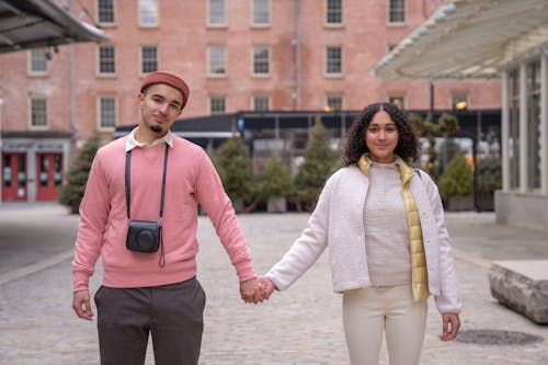 Positive Hispanic couple holding hands on street