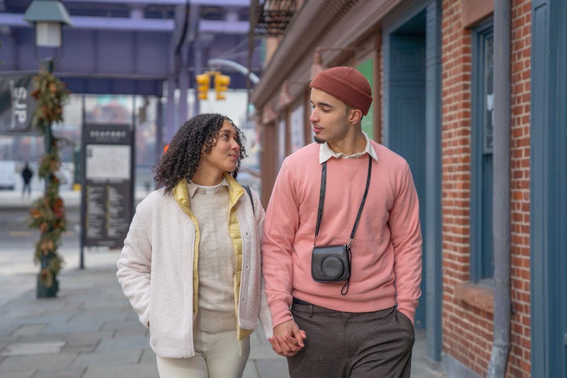 Free Romantic happy ethnic couple looking at each other while speaking and promenading in city Stock Photo