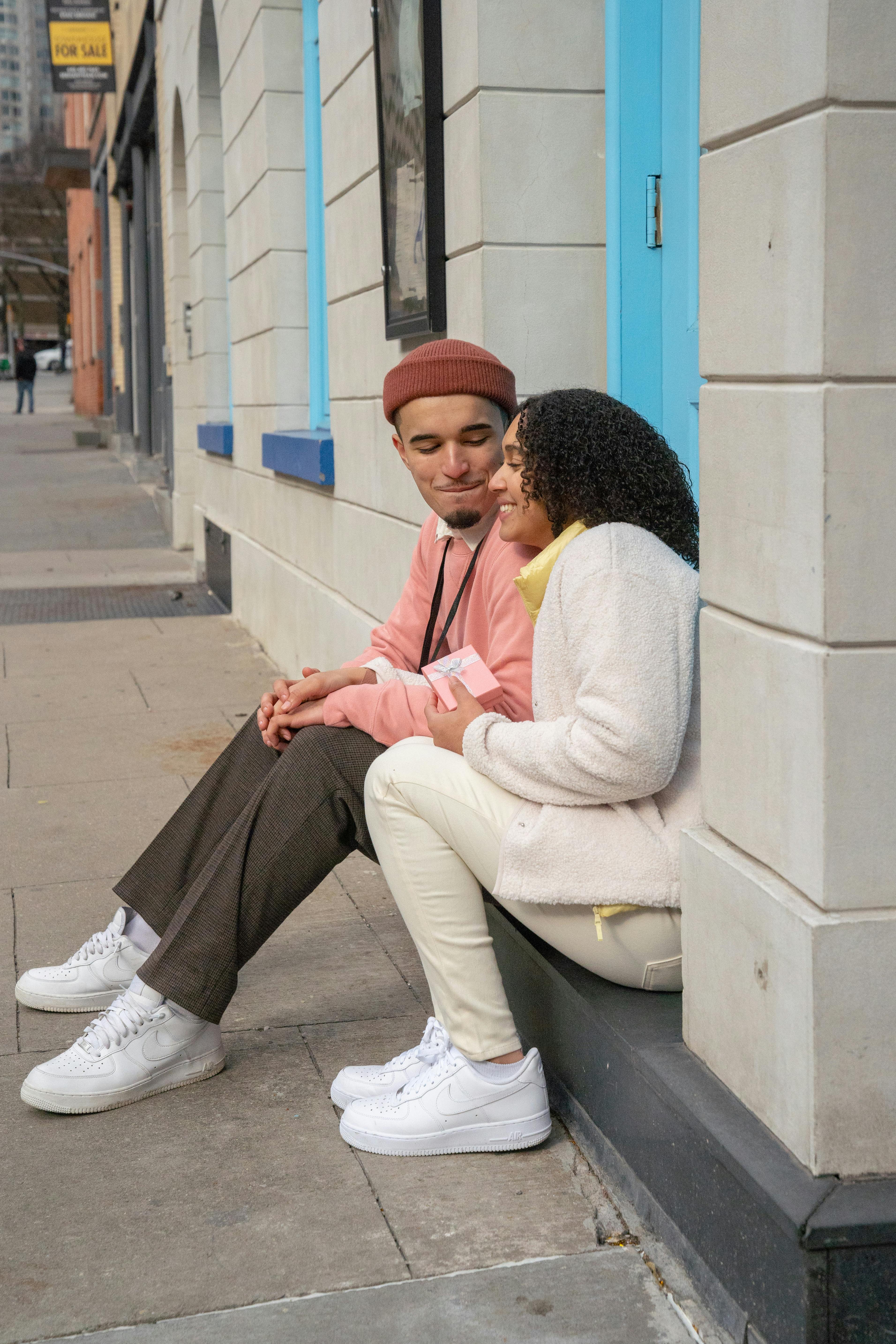 young hispanic positive couple smiling and resting on street