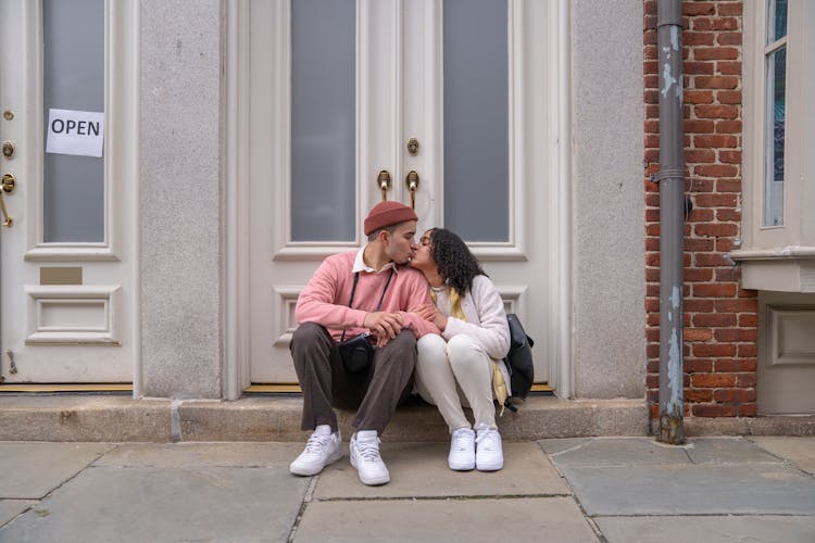 Enamored Young Ethnic Couple Kissing Near Doors Of Old Building