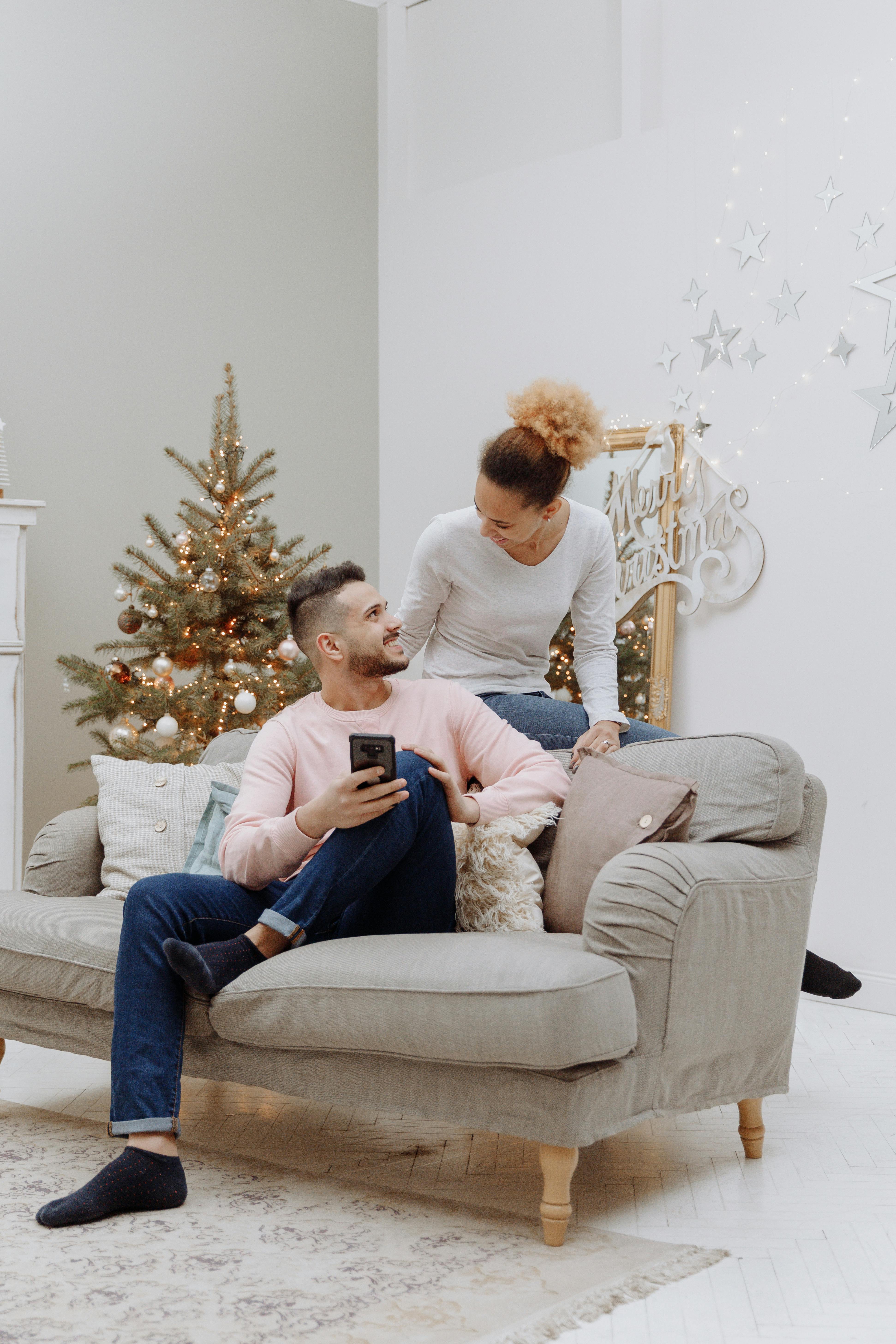 couple on sofa with phone near christmas tree