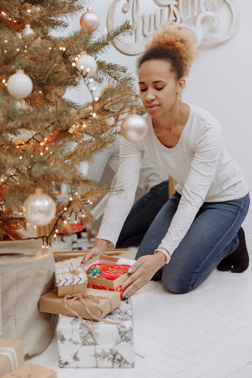 A Woman Placing Gifts Under a Christmas Tree