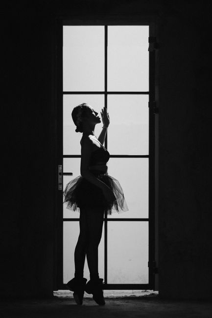 Black and white side view of female ballet dancer standing on tiptoes while looking up
