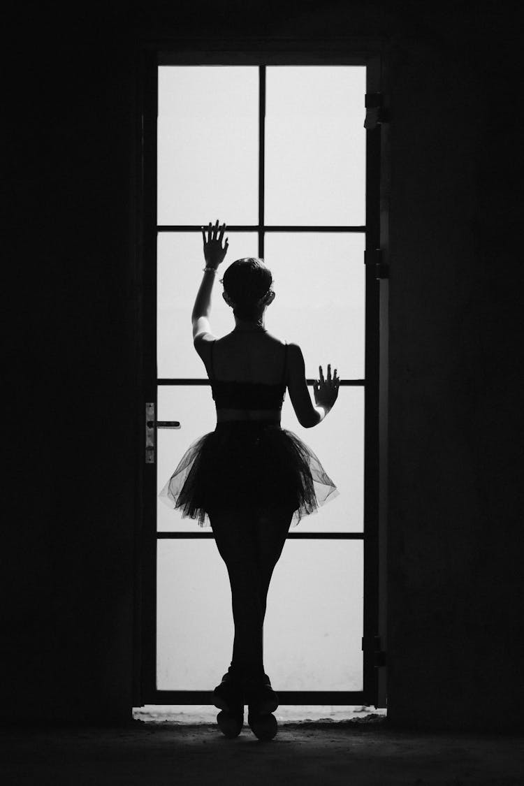 Unrecognizable Ballerina Touching Door In Darkness