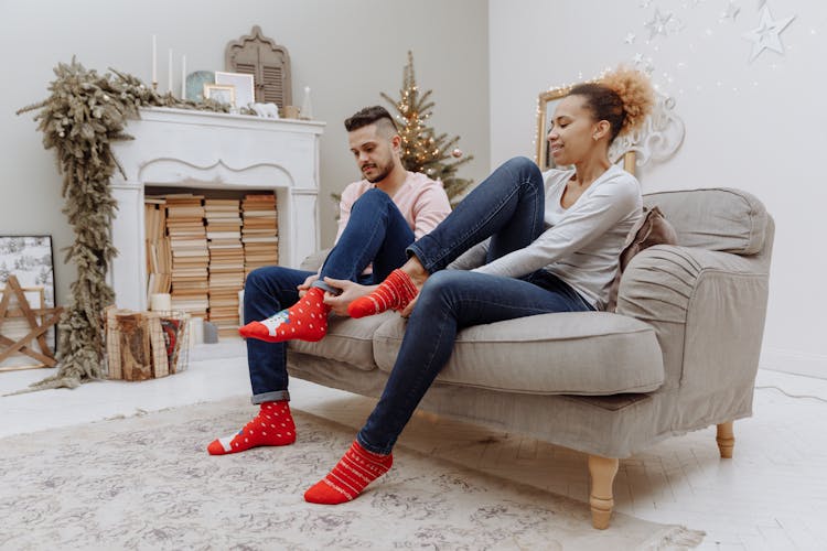 Man And Woman Sitting On Brown Couch Wearing Red And White Socks