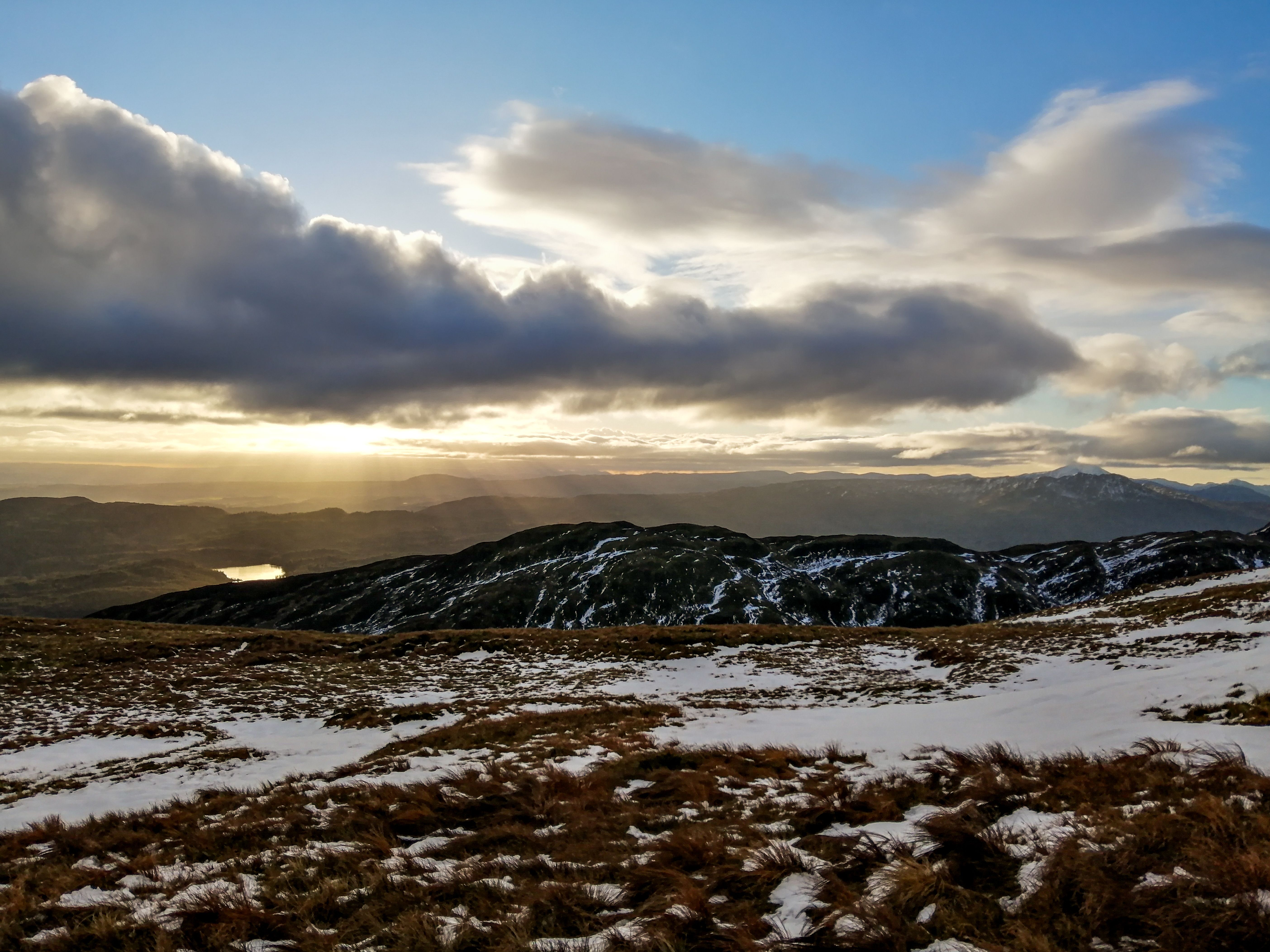 Snow lying across heather and peat moor under a low winter sun