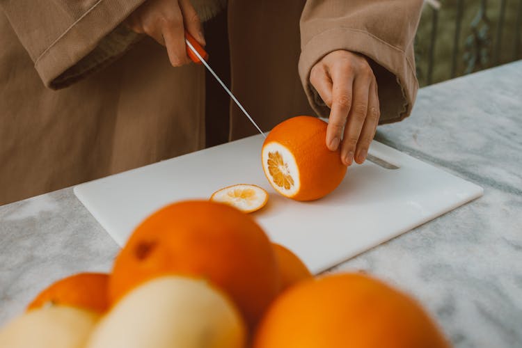 A Person Slicing An Orange