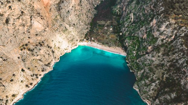 Stunning aerial view of a secluded beach cove surrounded by rocky cliffs and vibrant turquoise waters.