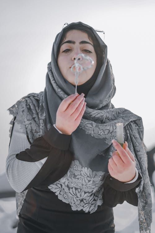 A Woman Wearing Hijab while Blowing a Soap Bubbles