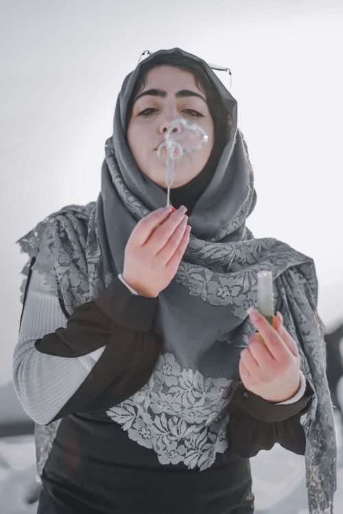 Free Muslim woman in hijab blowing soap bubbles in a peaceful outdoor setting. Stock Photo