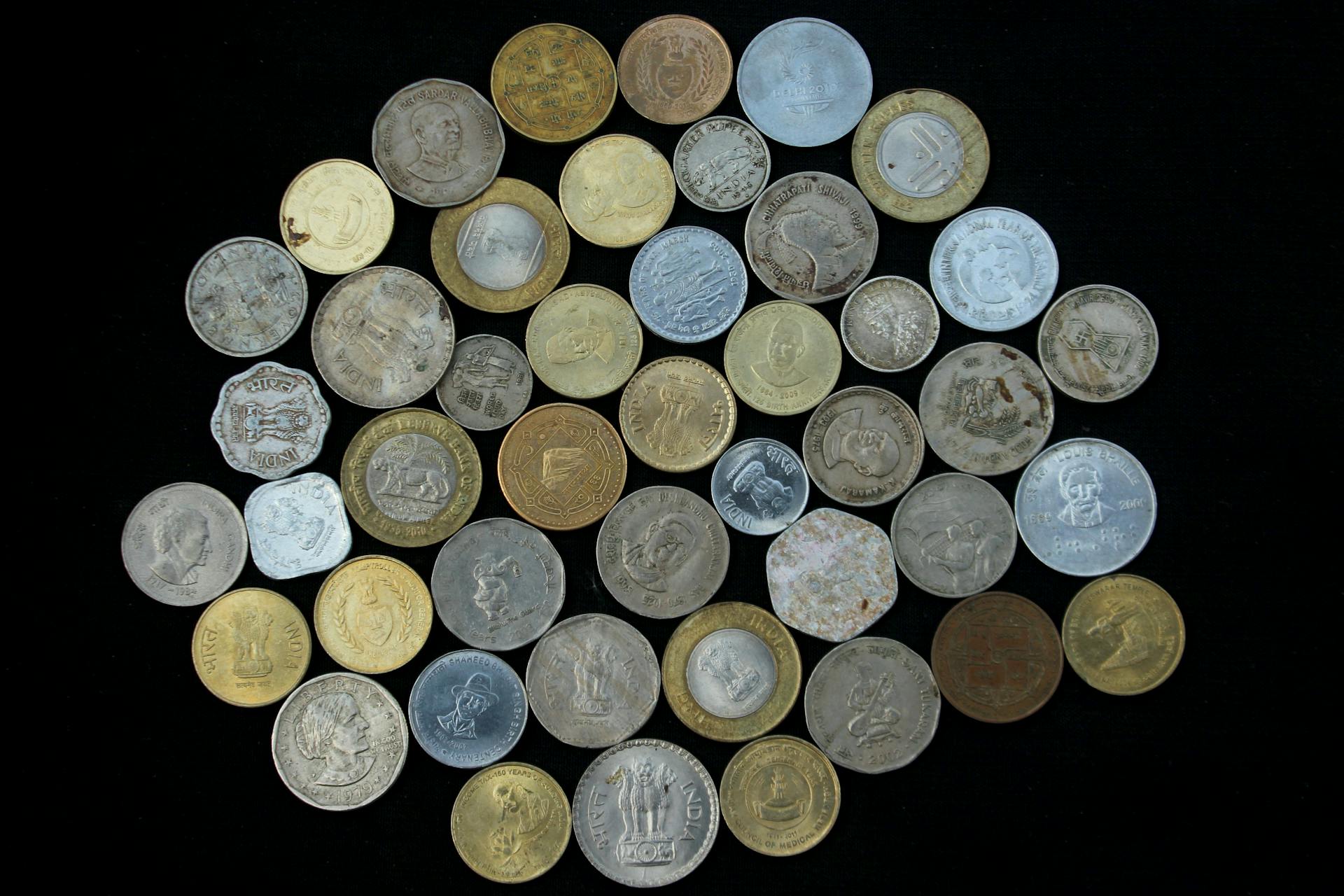 A variety of international coins displayed on a black background, showcasing different currencies and designs.