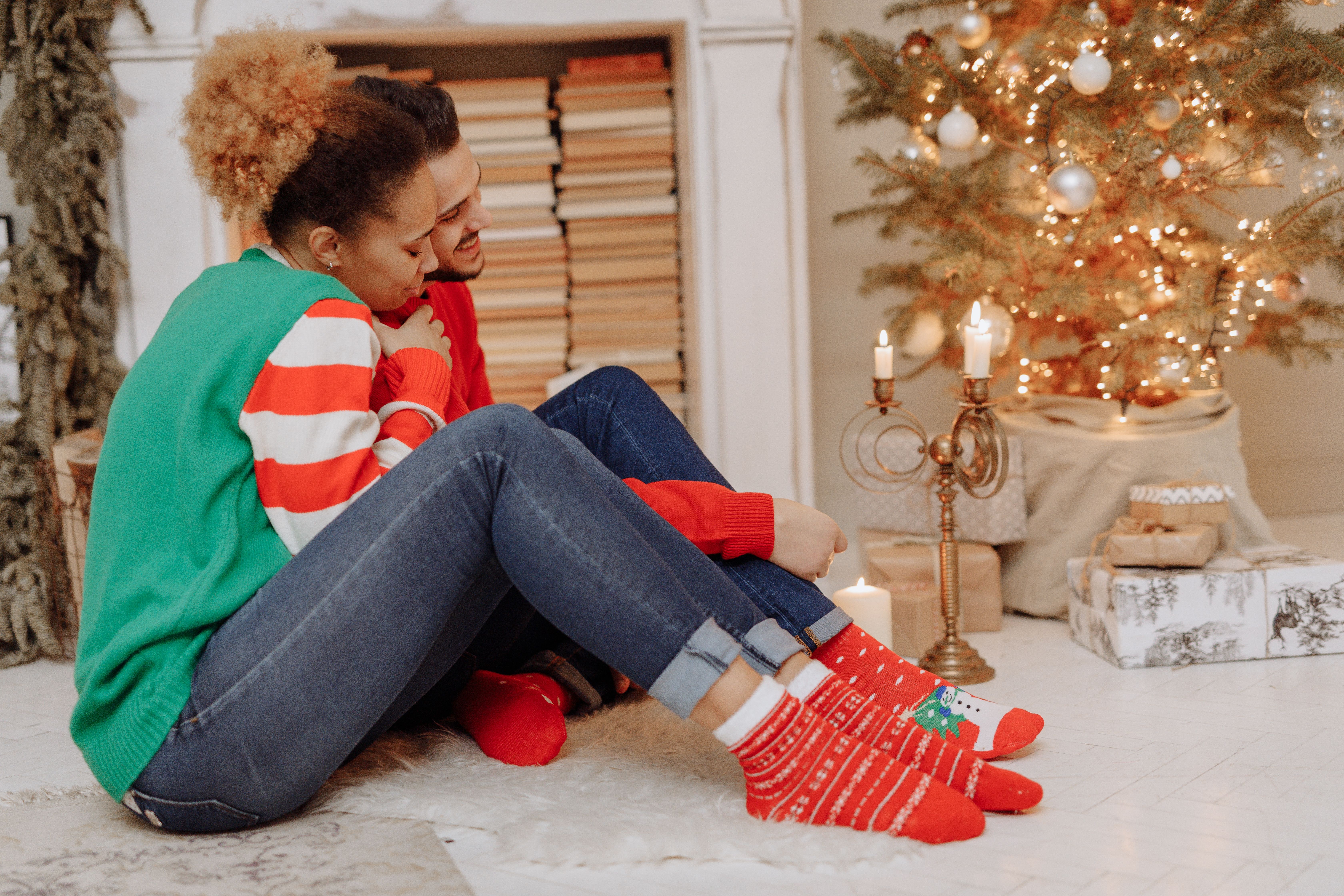 A couple in festive socks enjoying a cozy Christmas moment indoors.