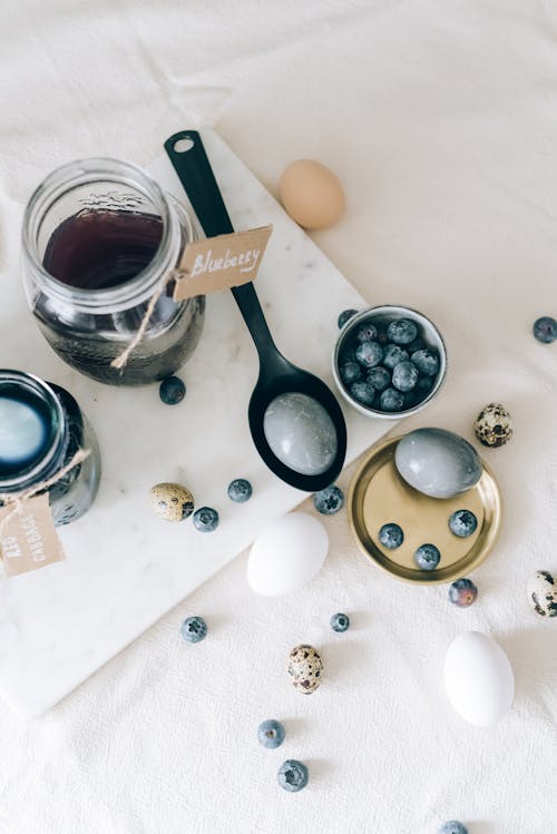 Blue Colored Eggs Beside A Bowl Of Blueberries